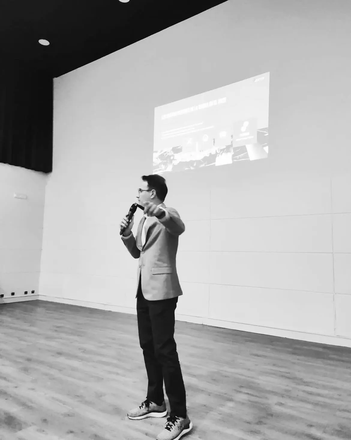 Alejandro Pinate con micrófono dirigiéndose directamente al público durante una conferencia